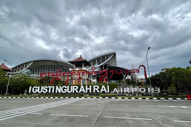 Pemandangan udara Bandara Internasional I Gusti Ngurah Rai (DPS) Bali dengan terminal berarsitektur khas dan pesawat di landasan.